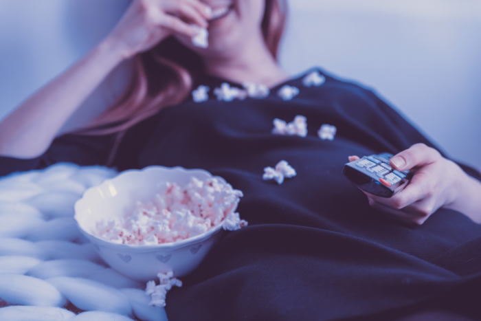 Home Projector Hire - Woman relaxing on the couch eating popcorn.